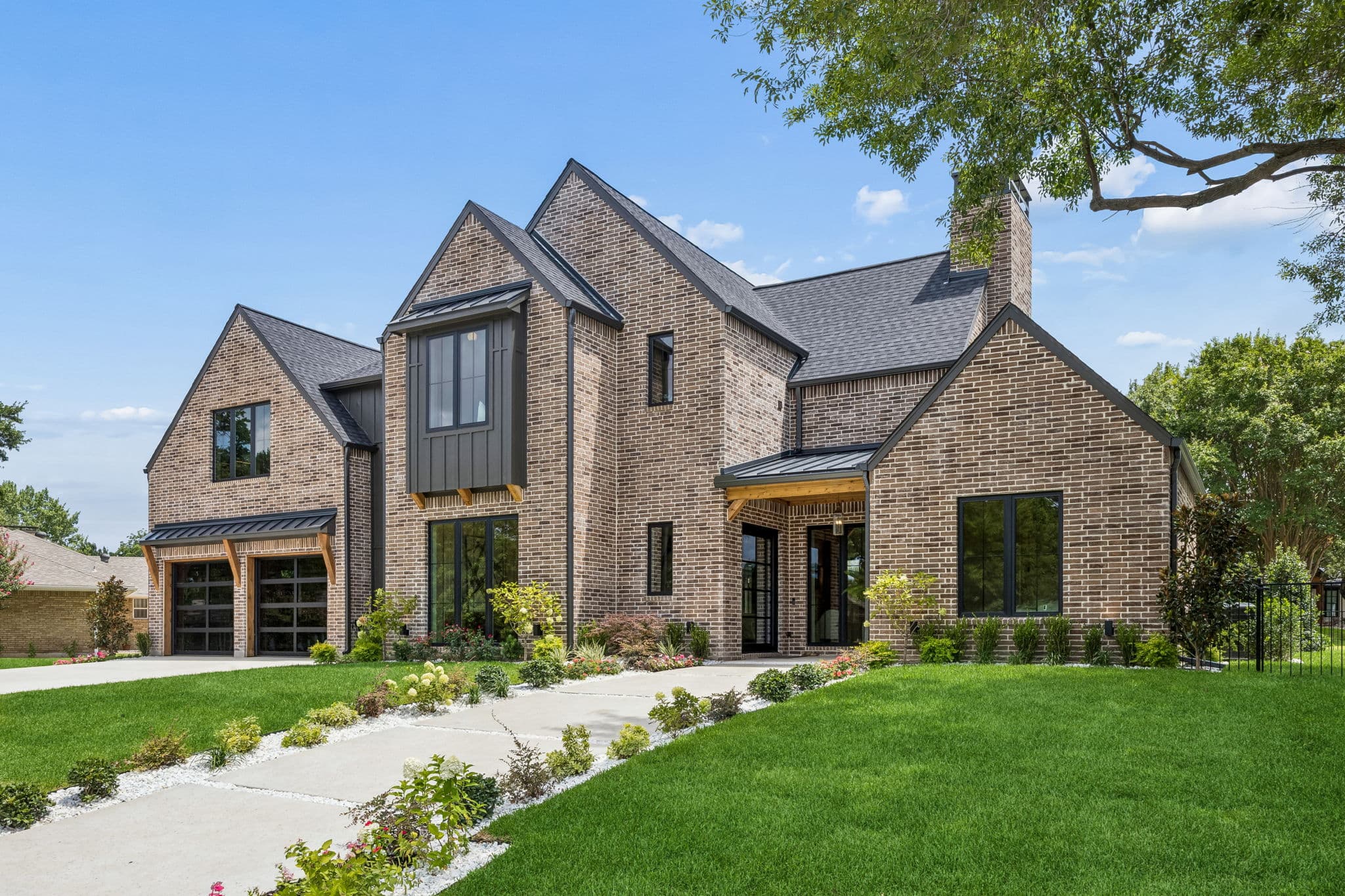 The front of 7308 Tangleglen, a brick house with steep gables and a stone chimney.